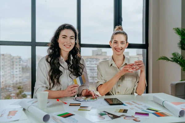 Portrait of blond and brunette women designers at their workplace. Selective focus.