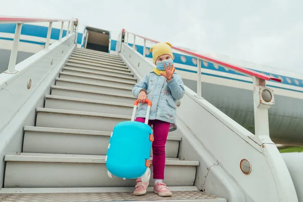 Niña Con Mascarilla Protectora Sosteniendo Maleta Agitando Mano Cerca Del — Foto de Stock