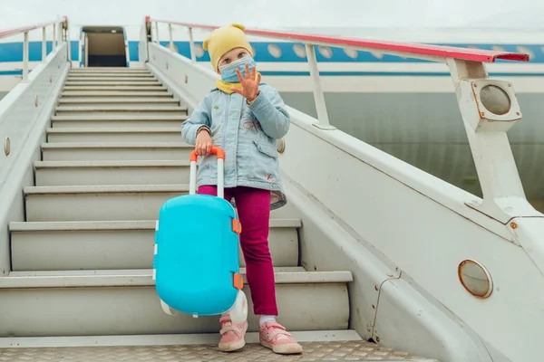 Niña Con Mascarilla Protectora Sosteniendo Maleta Agitando Mano Cerca Del — Foto de Stock