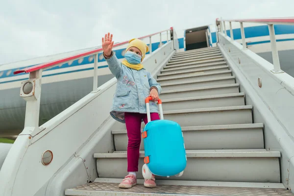 Niña Con Mascarilla Protectora Sosteniendo Maleta Agitando Mano Cerca Del — Foto de Stock