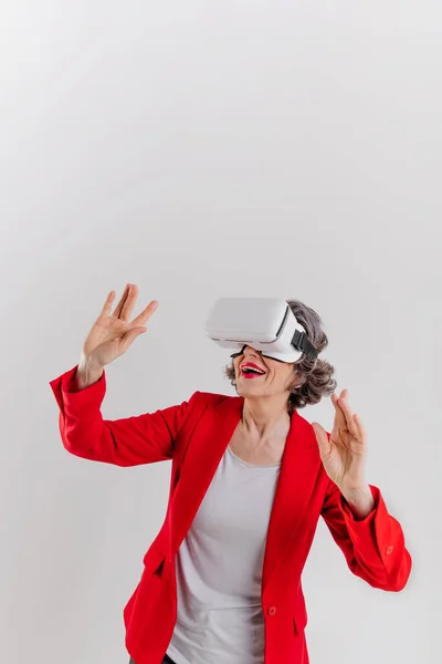 Mujer madura feliz usando gafas VR sobre fondo gris — Foto de Stock