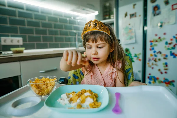 Liten flicka äter spannmål med mjölk i köket — Stockfoto