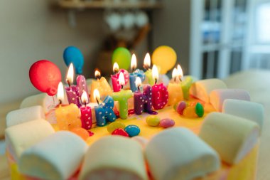 Doğum günü pastasında mumlar ve mektuplar. Mutfaktaki ahşap masada yenebilir şeker balonları ile süslenmiş mutlu yıllar. Seçici odak.