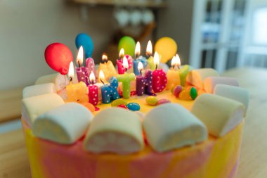 Doğum günü pastasında mumlar ve mektuplar. Mutfaktaki ahşap masada yenebilir şeker balonları ile süslenmiş mutlu yıllar. Seçici odak.