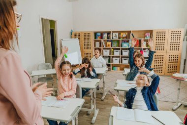 Elementary school students rising hands in the classroom