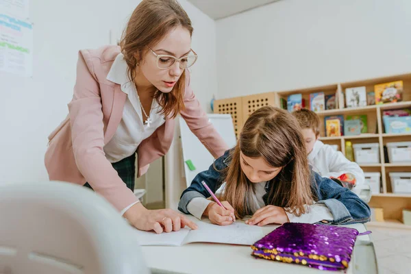 Žena učitel pomáhá školačka ukazuje na něco na svém notebooku — Stock fotografie