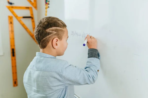 Student základní školy píše na tabuli plstěným hrotem ve třídě — Stock fotografie