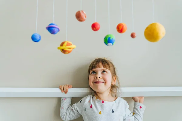 Menina brincando com planetas de brinquedo feitos por si mesma de argila de moldagem colorida interior — Fotografia de Stock