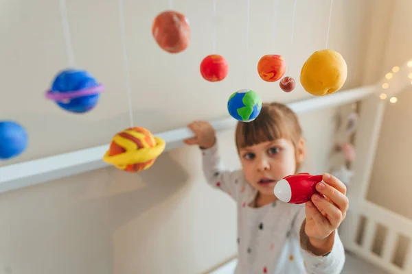 Menina brincando com planetas de brinquedo feitos por si mesma de argila de moldagem colorida interior — Fotografia de Stock