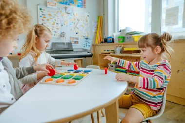 Anaokulu öğrencileri ahşap geometrik formları sıralıyorlar. Anaokulunda ya da kreşte oyun öğrenme. Eğitim konsepti. Seçici odak.
