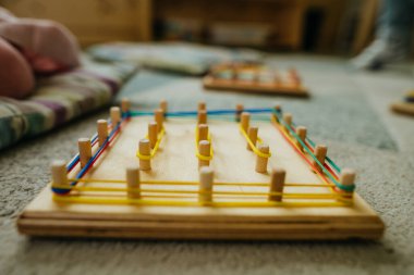 Anaokulu öğrencileri lastik bantlarla oynuyorlar. Tahta tahtadan yapılmış matematiksel bir manipülatif. Anaokulunda oyuncak öğrenmek. Eğitim konsepti. Seçici odak.