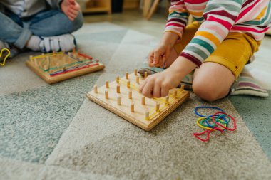 Anaokulu öğrencileri lastik bantlarla oynuyorlar. Tahta tahtadan yapılmış matematiksel bir manipülatif. Anaokulunda oyuncak öğrenmek. Eğitim konsepti. Seçici odak.