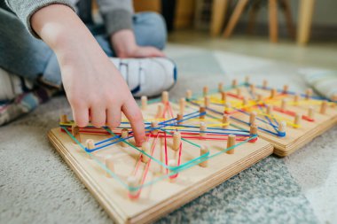 Coğrafi paket lastiğiyle oynayan çocuğa yakın çekim. Tahta tahtadan yapılmış matematiksel bir manipülatif. Seçici odak.