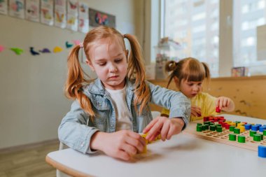Anaokulu öğrencileri ahşap mozaikle oynuyorlar. Hayal gücünü ve yaratıcılığını geliştirmek için harika. Doğal malzeme konseptinden eğitici oyuncaklar. Seçici odak.