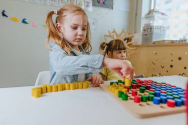 Anaokulu öğrencileri ahşap mozaikle oynuyorlar. Hayal gücünü ve yaratıcılığını geliştirmek için harika. Doğal malzeme konseptinden eğitici oyuncaklar. Seçici odak.