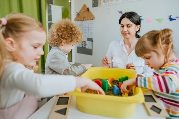 Studenti Předškolního Věku Hledají Dřevěné Geometrické Tvary Nádobě Syrovými Fazolemi — Stock fotografie