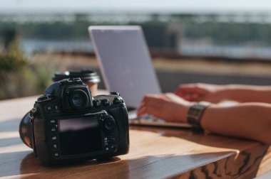 Dışarıdaki kafede dizüstü bilgisayarda çalışan serbest çalışan bir kadının yanındaki masada. Serbest çalışma konsepti. Kameraya seçici odaklanma.