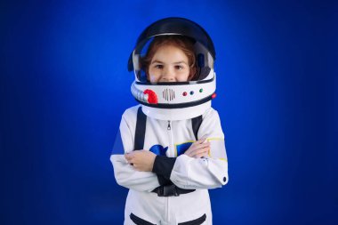 Astronot kostümü ve kask giyen genç kız telif alanı olan koyu mavi arka planda duruyor. Uzay elbisesi içindeki güzel kızın portresi..
