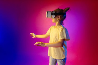 Renkli neon arka planda VR gözlük kullanan sevimli bir genç kız ve mesaj için boş bir alan..