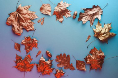 Mavi arkaplanda altın yaprakların çerçevesi ve metin için boş alan. Sonbahar doğal konsepti. Üst manzara, düz uzanma.