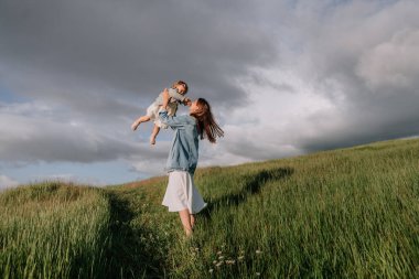 Genç, güzel bir kadın ve tapılası kızı günlük kıyafetler giyip dışarıda eğleniyorlar..