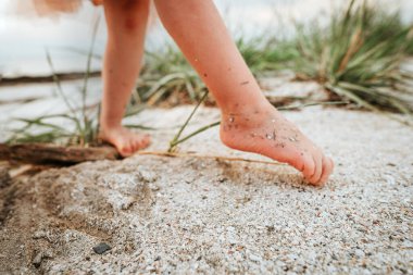 Kapalı kapılar ardında küçük bir kız gün batımında kumların üzerinde resim çizerken eğleniyor.
