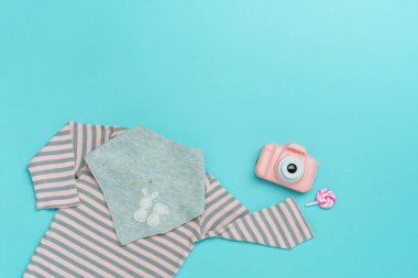 Çocuk kıyafetleri. Romper ve bib organik pamuktan ve oyuncak fotoğraf makinesinden mavi arkaplanda mesaj için boş alan. Üst manzara, düz uzanma.