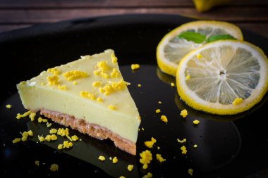Siyah tabakta limonlu tatlı ve limon dilimleri.