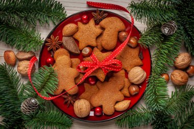 Noel - kırmızı tabakta ev yapımı zencefilli ekmek, yanındaki yeşil köknar, anason, fındık ve koni