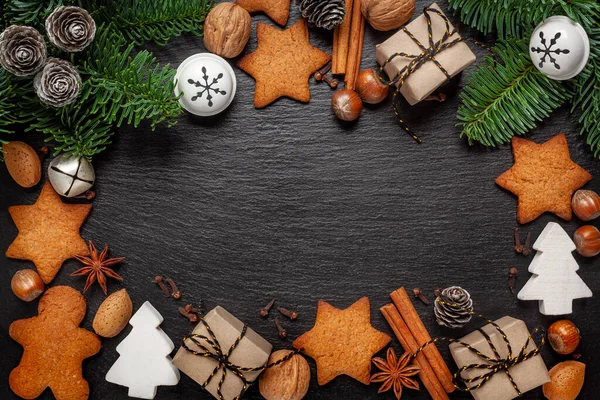 Noel - siyah bir arkaplanda ev yapımı zencefilli ekmek, fındık, koni, zencefilli kek baharatları ve Noel süslemeleri kompozisyonu - metin için alan