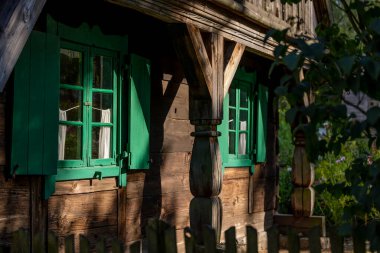 Eski, ahşap, yeşil pencereli, odunlardan yapılmış bir kır evinde dekoratif panjurlar, bahçeye bakan bir pencere - Warmia ve Masuria, Polonya