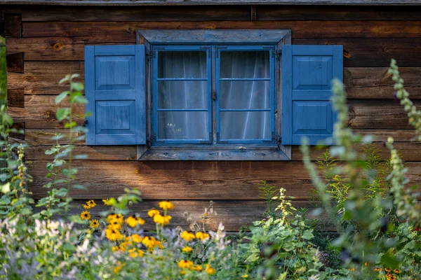丸太で作られたカントリーハウスのシャッター付きの古い 木製の 青い塗装窓 美しい開花庭を見下ろす窓 ポーランドのウォーミアとマスーリア — ストック写真