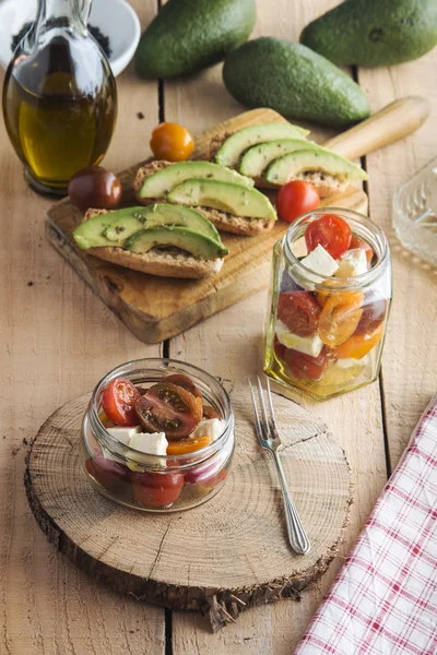 Salade de tomates et fromage feta dans un bocal en verre et pain grillé à l'avocat — Photo