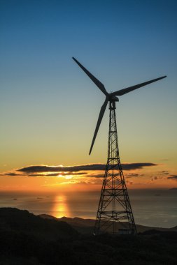 gün batımında rüzgar türbini çimen Park