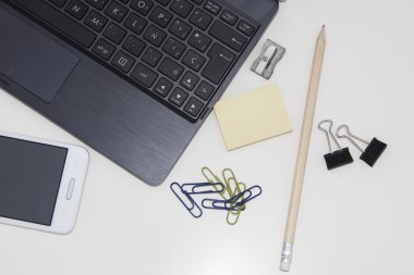 çalışma alanı ile dizüstü bilgisayar, cep telefonu, klipler, kalem, posta o içinde beyaz