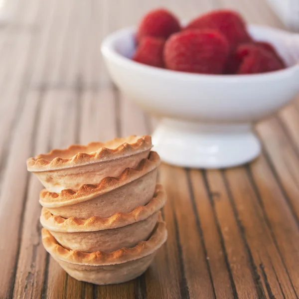 Cooking sweet tartlets with raspberry on wooden table — Stock Photo, Image