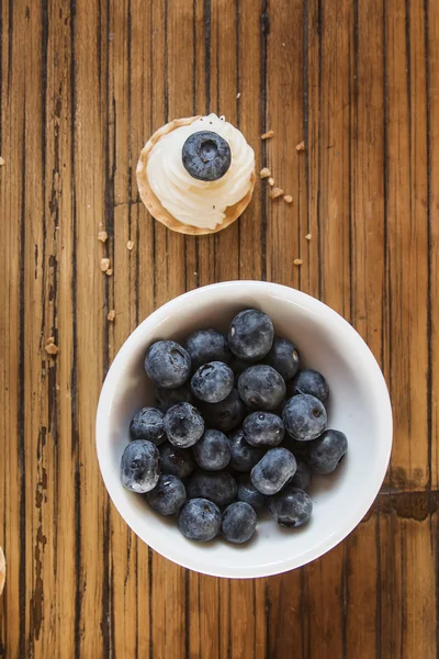 Cookingh sweet tartlets filled with cream and  blueberry on wood — Stock Photo, Image