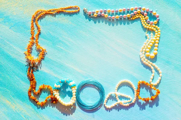 A set of sea natural jewelry. Space for the text. Coral amber pearl and bone jewelry on a blue background. Top view. High quality photo