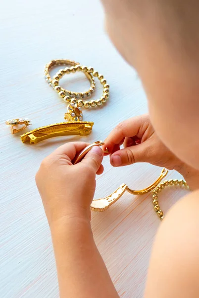 hands of child play with gold jewelry and bijouterie, on white background. concept of womens happines High quality photo