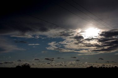 Dramatik gökyüzü manzarası ve yağmurlu yaz mevsiminde olgunlaşmamış buğday tarlası. Kara fırtına bulutlu toprak yol