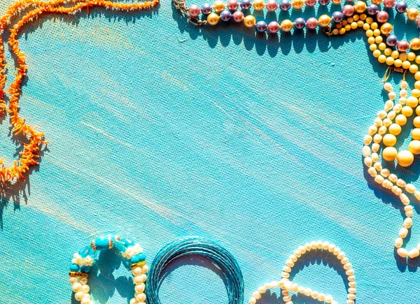 En uppsättning naturliga smycken. Utrymme för texten. Korall bärnsten pärla och ben smycken på en blå bakgrund. Ovanifrån. — Stockfoto