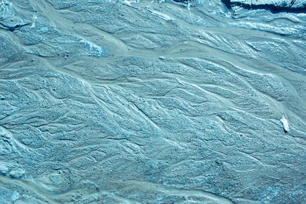 Modrá písková textura s vlnitými liniemi a proudem vody v teplých barvách. Písčitá plocha po dešti — Stock fotografie