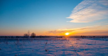 Rusya 'nın Leningrad bölgesindeki Vsevolozhsk' ta gün batımında bir kar tarlasında kış manzarası. Yüksek kalite fotoğraf