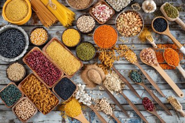 Tahta masada çeşitli organik baklagiller var. Kavanozda ve kaşıkta kurutulmuş bezelye ve bakla konsepti. 