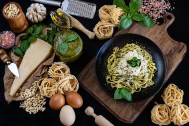 Ahşap masada pesto sosu hazırlığı. Fesleğen, çam fıstığı, havan, parmesan peyniri ve mutfak tezgahında rende..