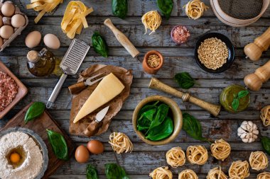 İki kadının elleri parmesan peyniri, fesleğen, çam fıstığı ve diğer malzemelerle pesto sosu hazırlıyor. Mutfak tezgahında yemek hazırlığı.. 