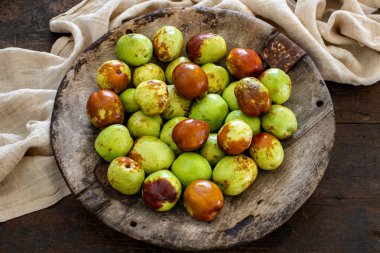 Tahta kırsal arka planda, kasedeki taze meyve suları. Yuvarlak meyveler tabakta, masa manzaralı.. 