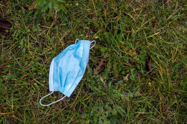 Açık mavi bir yüz maskesi çimlerin üzerinde yatıyor.