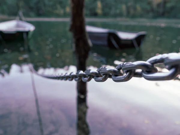 a rowing boat is attached to a steel chain, which floats on a lake