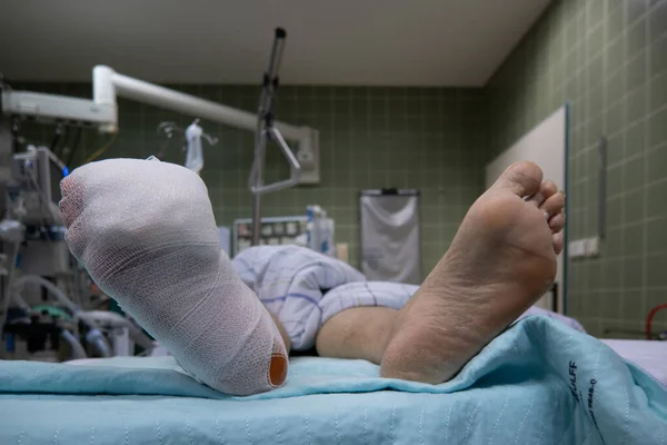 the foot of a patient lying in a hospital bed is wrapped with a bandage